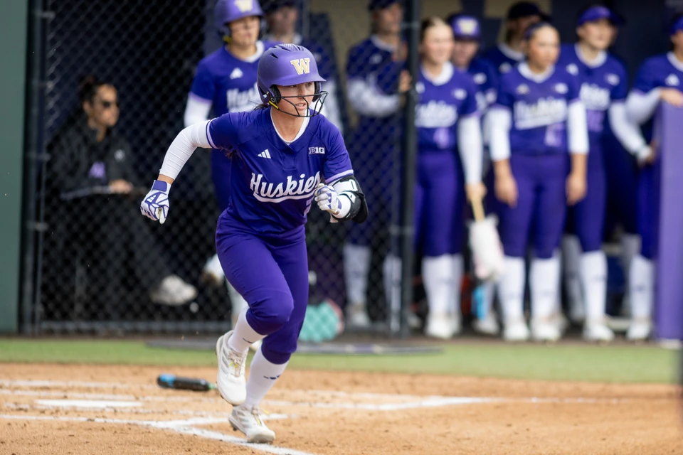 Washington softball player running in a purple helmet